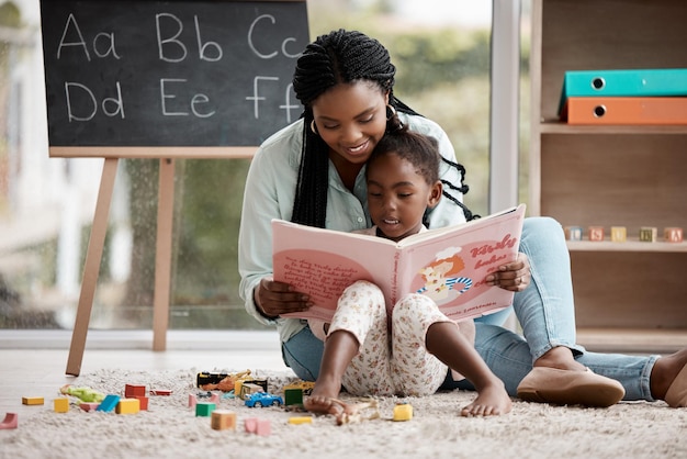 A ella le encantan las buenas historias Foto de una mujer leyendo un libro a su hija mientras está sentada en casa