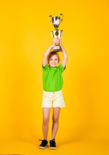 Ella es campeona Victoria y gana Premio merecido Logro deportivo concepto de éxito deportivo feliz día de los niños infancia feliz niña pequeña sostiene la recompensa dorada de la copa del campeonato Combate final