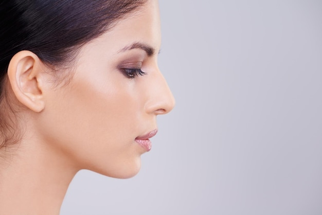 Ella es una foto de estudio de belleza impecable de una hermosa mujer morena contra un fondo gris