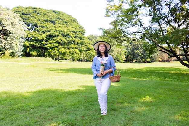 Ella está caminando y sosteniendo la canasta y el ramo de flores.