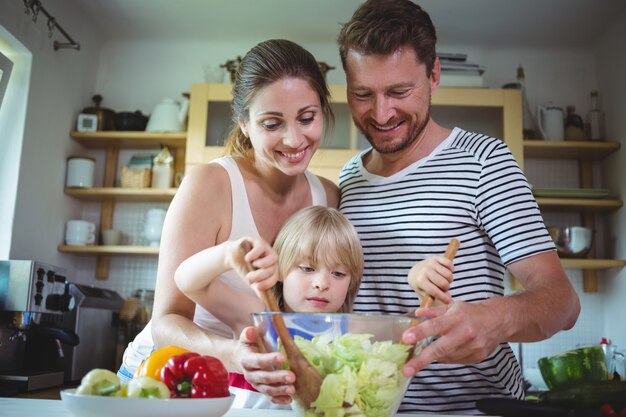 Eltern beobachten, wie ihre Tochter den Salat mischt