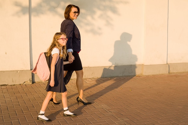 Eltern, die Kind an der Hand halten, gehen zur Schule