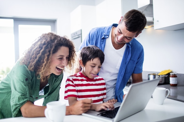 Eltern, die Laptop mit Sohn in der Küche verwenden