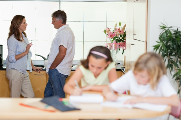 Eltern, die mit den Kindern tun Hausaufgaben vor ihnen sprechen