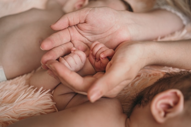 Foto eltern halten sanft die hände kleiner kinder, nahaufnahme der hand des babys und eltern, eltern kümmern sich um die ...