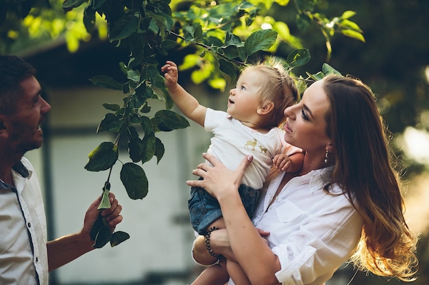 Eltern mit baby genießen picknick auf einem bauernhof mit apfel- und kirschbäumen.