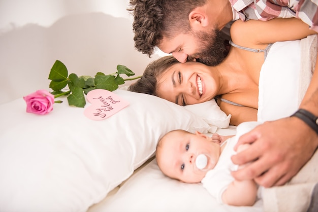 Eltern mit Baby im Bett zu Hause.