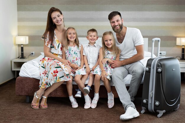 Eltern mit Kindern sitzen auf dem Bett im Hotel und lachen Reisen mit Kindern