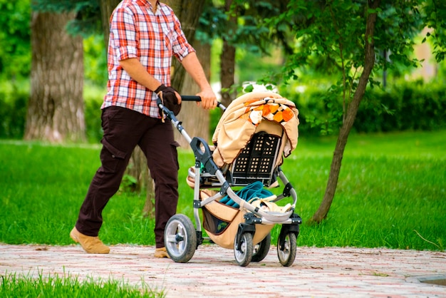 Eltern mit Kinderwagen, die im Freien in den öffentlichen Parkgassen der Stadtstraße spazieren gehen