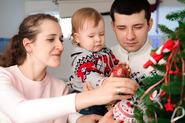 Eltern mit Tochter verkleiden Weihnachtsbaum.