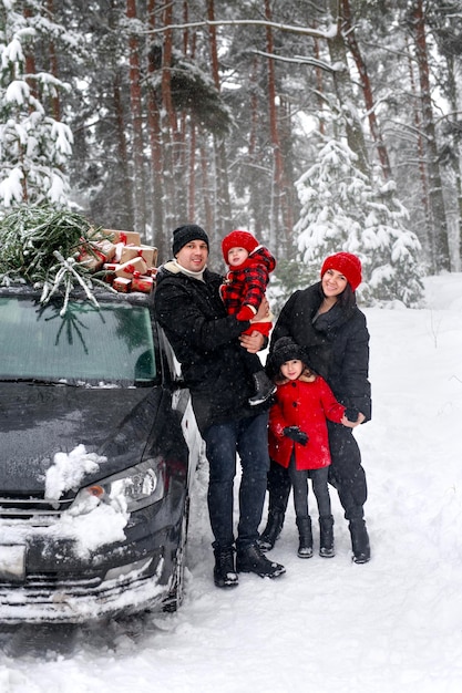 Eltern mit Töchtern stehen mit untergetauchtem Weihnachtsbaum am Auto