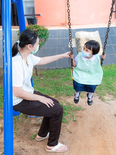 Eltern nehmen Schüler mit zu Familienaktivitäten Spielen Sie auf dem Spielplatz, schaukeln Sie leicht schaukeln und haben Sie abends nach der Schule Spaß zu zweit