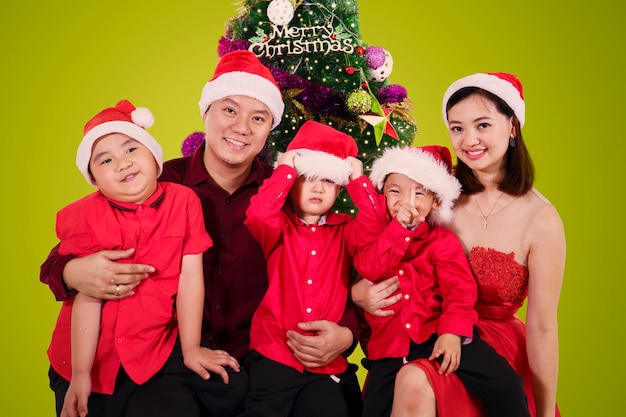 Eltern sitzen mit ihren Söhnen neben einem Weihnachtsbaum