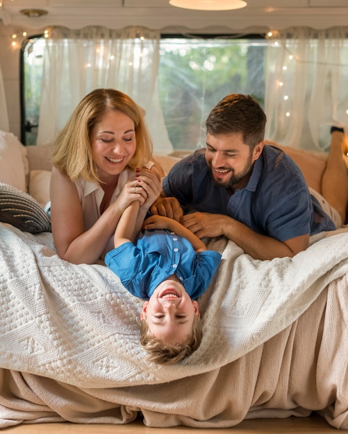 Foto eltern spielen mit ihrem sohn im bett