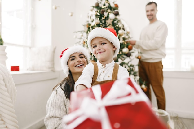 Eltern und ihr kleiner Sohn haben Spaß und spielen zur Weihnachtszeit drinnen zusammen