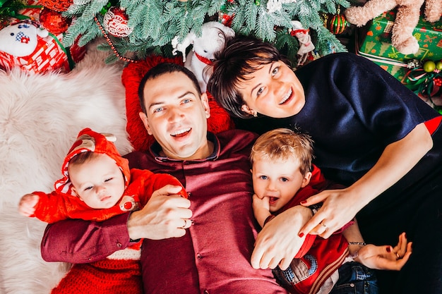 Eltern und ihre zwei Söhne liegen unter dem Weihnachtsbaum