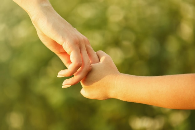 Eltern und Kind halten sich im Freien an den Händen