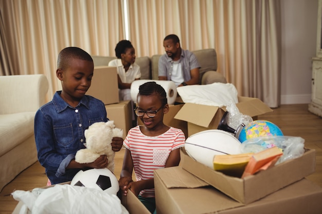 Eltern und Kinder entpacken Pappkartons im Wohnzimmer