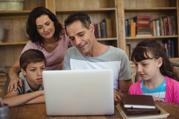 Eltern und Kinder mit Laptop auf Tisch im Arbeitszimmer