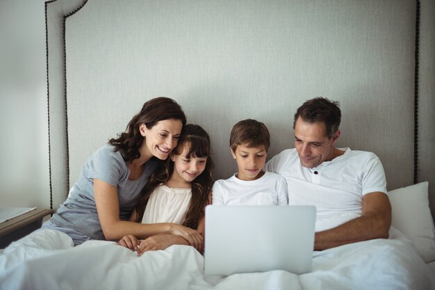 Eltern und Kinder mit Laptop im Bett