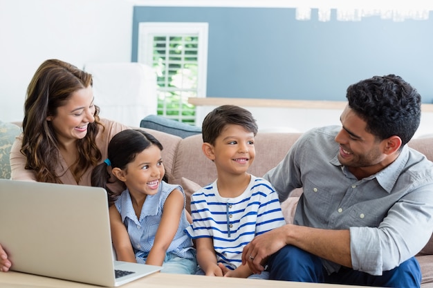 Eltern und Kinder mit Laptop im Wohnzimmer