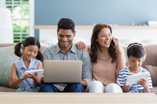 Eltern und Kinder mit Laptop und digitalem Tablet im Wohnzimmer