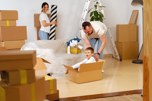 Eltern und Sohn packen Kartons und ziehen in ein neues Zuhause