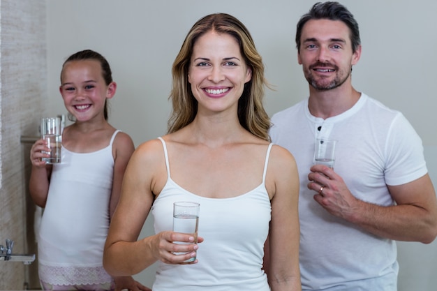 Eltern und Tochter, die ein Glas Wasser im Badezimmer halten