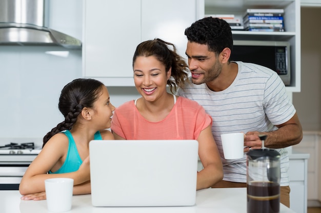 Eltern und Tochter mit Laptop in der Küche zu Hause