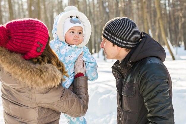 Elternschaft, Mode, Jahreszeit und Menschenkonzept - glückliche Familie mit Kind in Winterkleidung im Freien.