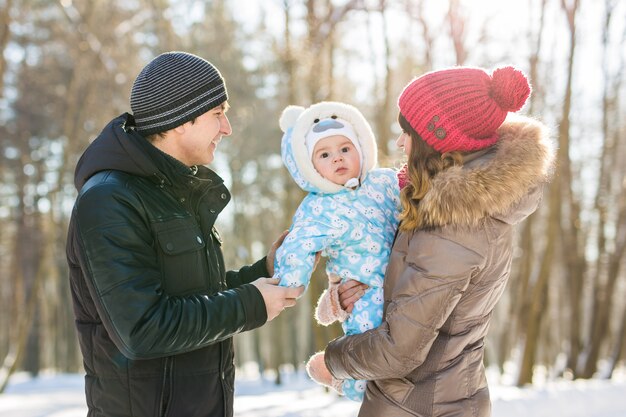 Elternschaft, Mode, Jahreszeit und Menschenkonzept - glückliche Familie mit Kind in Winterkleidung im Freien.