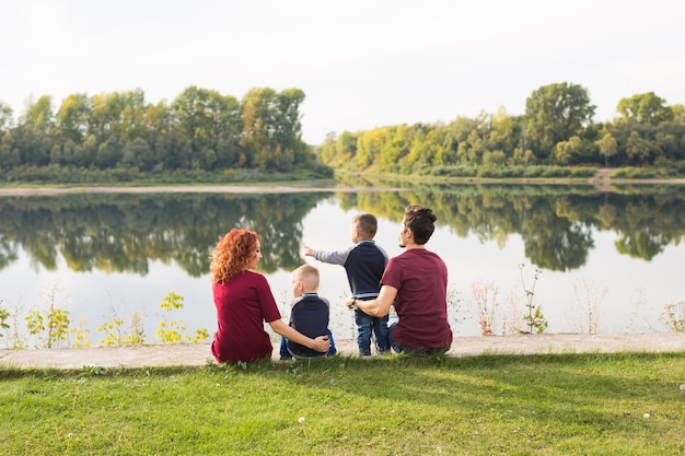 Elternschaft, Natur, Menschenkonzept - Familie mit zwei Söhnen, die in der Nähe des Sees sitzen.