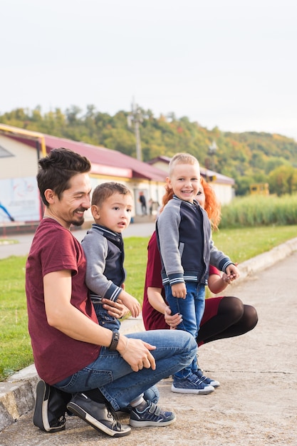 Elternschafts-, Kindheits- und Familienkonzept - Eltern und zwei männliche Kinder gehen im Park spazieren und schauen sich etwas an