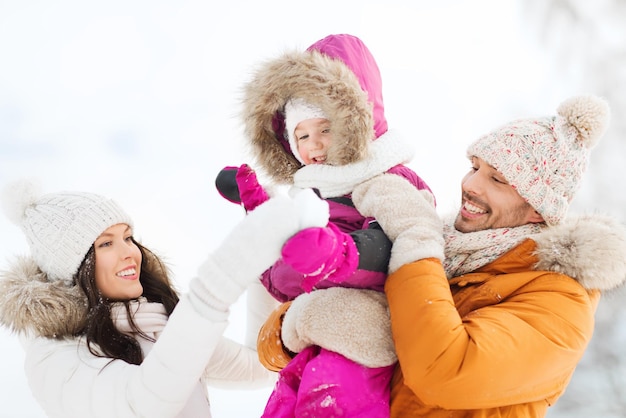 Foto elternschafts-, mode-, jahreszeit- und leutekonzept - glückliche familie mit kind im winter kleidet draußen