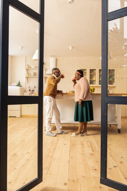 Em casa. belo casal feliz em pé juntos na cozinha enquanto bebem chá lá