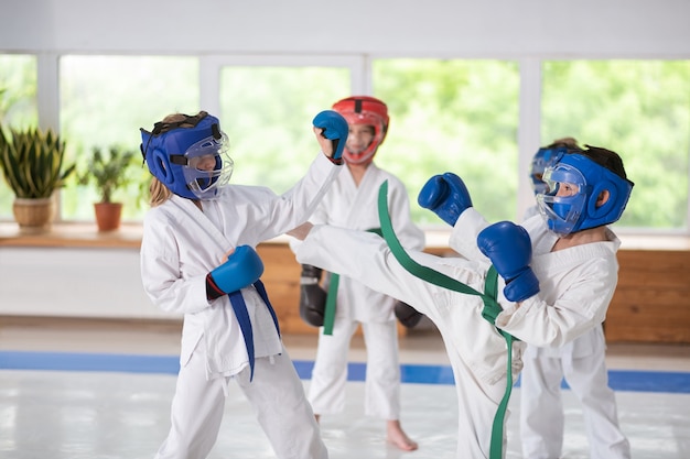 Em luvas de boxe. Garoto e garota esportivos ativos usando capacetes e luvas de boxe lutando