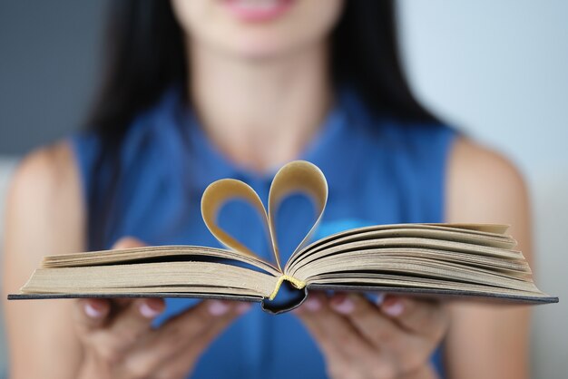 Em mãos femininas, as folhas do livro são dobradas em forma de coração.