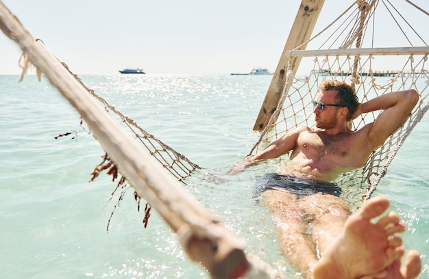 Em óculos de sol Jovem europeu tem férias e aproveita o tempo livre na praia do mar