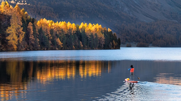 Em paddleboard no lago de montanha no outono