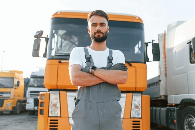 Em pé e posando para a câmera Homem de uniforme fazendo serviço para caminhão grande