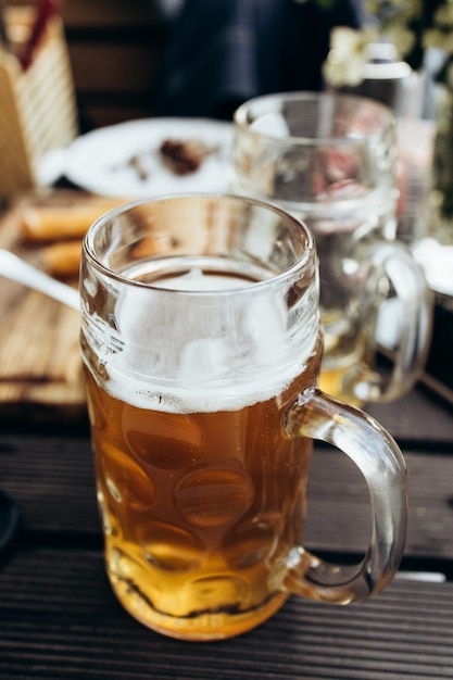 Em um café de rua em uma mesa de madeira há uma caneca incompleta de cerveja fresca