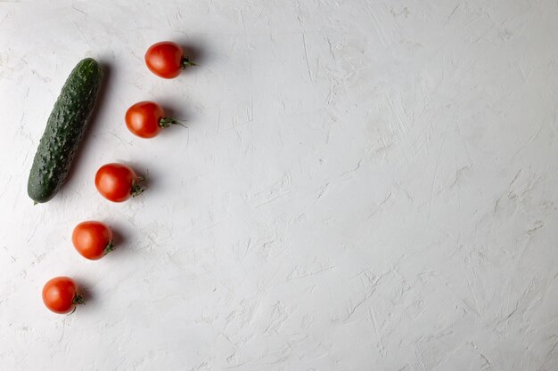 Em um fundo branco estão pepino e tomate. Copie o espaço.