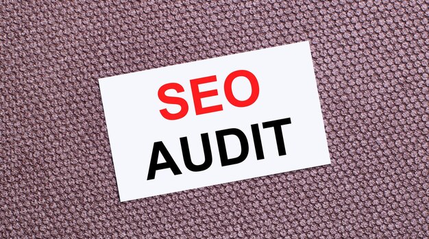 Em um fundo marrom, um cartão retangular branco com o texto SEO AUDIT