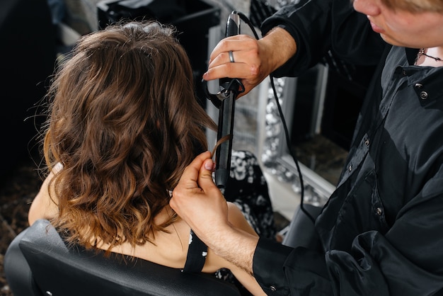 Em um lindo e moderno salão de beleza, um estilista profissional faz um corte de cabelo e penteado para uma jovem. Beleza e moda.