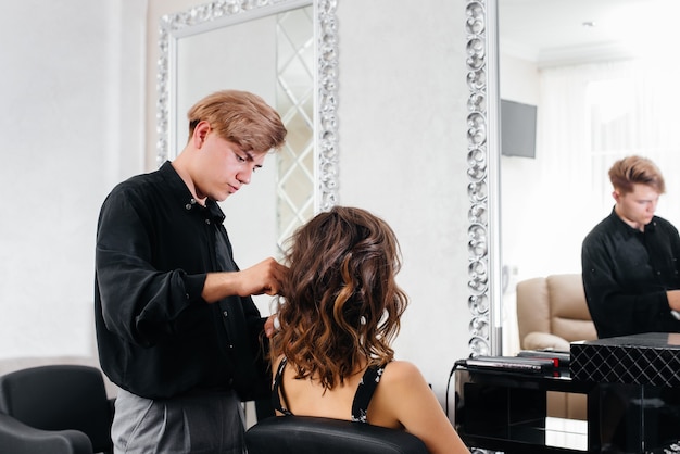 Em um salão de beleza, um estilista profissional faz um penteado para uma jovem