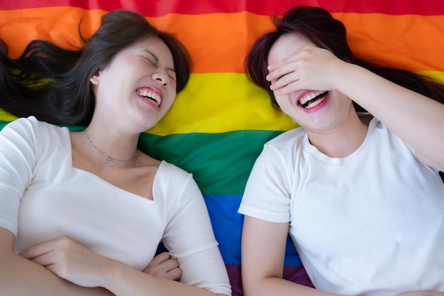 Em uma bandeira arco-íris um casal LGBT ri alegremente