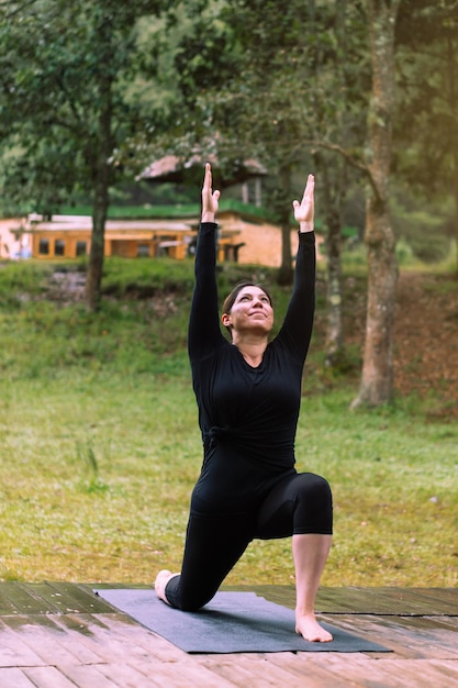 Em uma floresta, uma mulher pratica ioga ao ar livre. Saúde física e mental.