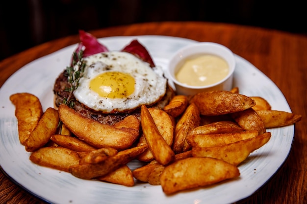 Em uma mesa de madeira um prato com bife picado com batatas de ovo em molho estilo country