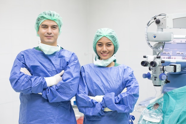 Em uma moderna sala de cirurgia médico e equipe olhando para a câmera com um sorriso.