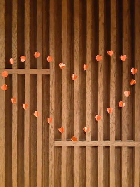 Em uma parede de madeira com pranchas verticais revestidas com um formato de coração feito de muitos pequenos corações vermelhos